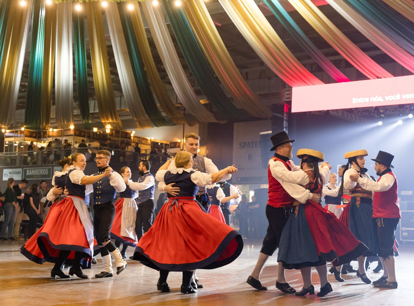 Grupo em trajes típicos alemães dança em apresentação cultural na Oktoberfest.