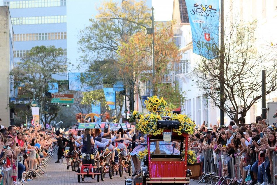 Desfile da Oktoberfest em rua movimentada, com carros decorados