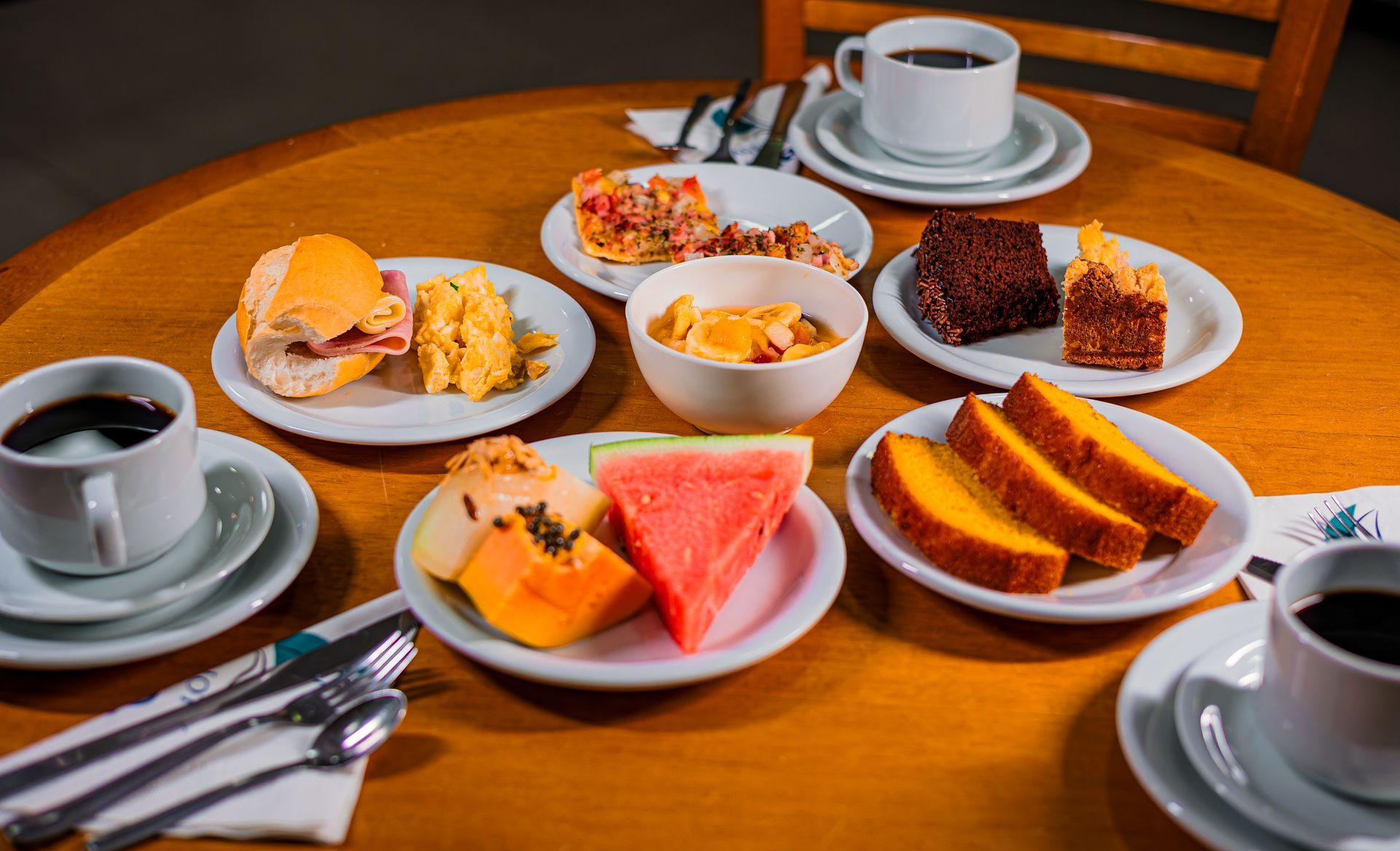 Mesa de café da manhã com pão, frutas, café e bolos variados