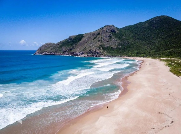 Praia cercada por montanhas e vegetação na Lagoinha do Leste.