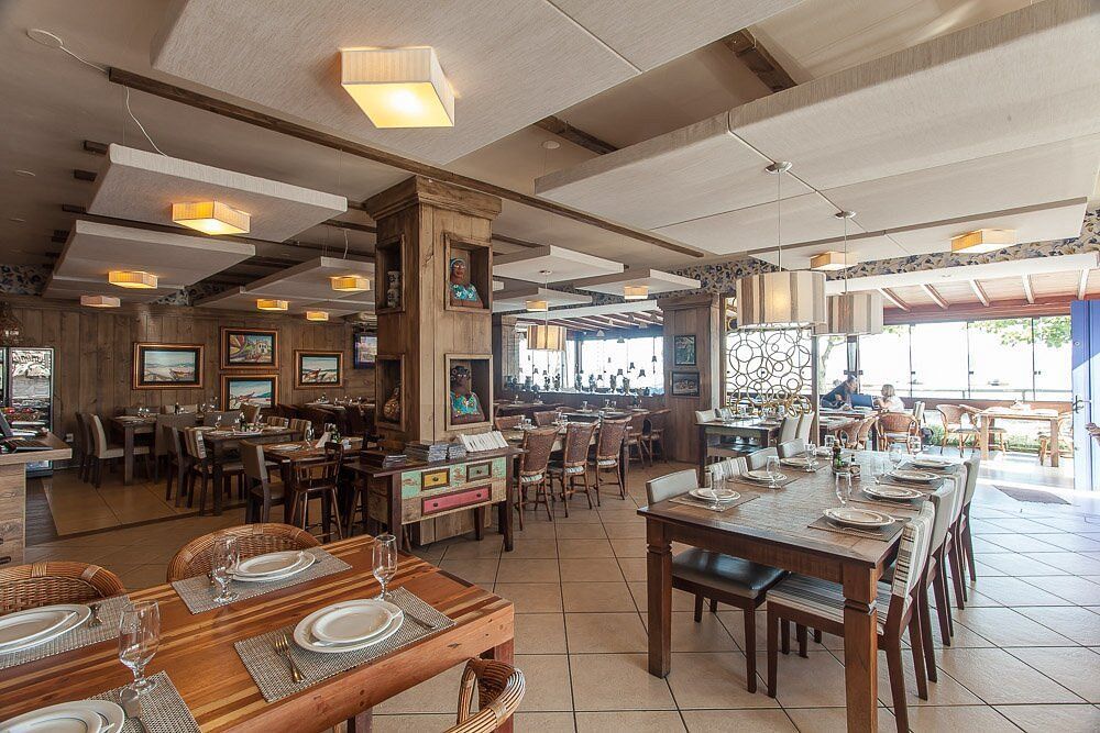 Ambiente de restaurante elegante e acolhedor, com mesas de madeira bem postas, iluminação suave e decoração