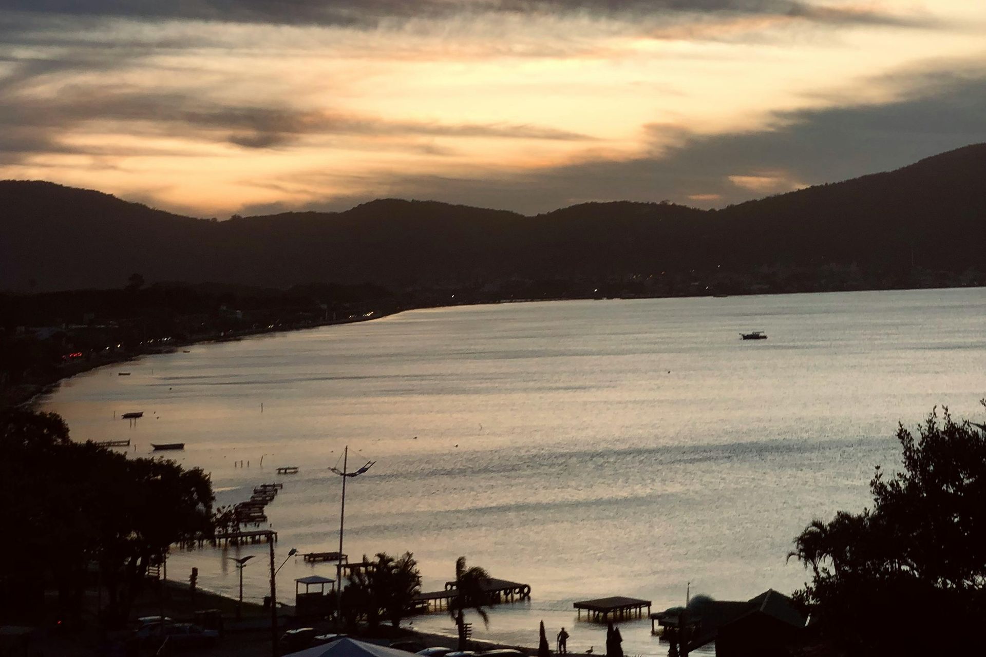 Vista do mar ao entardecer com montanhas ao fundo.