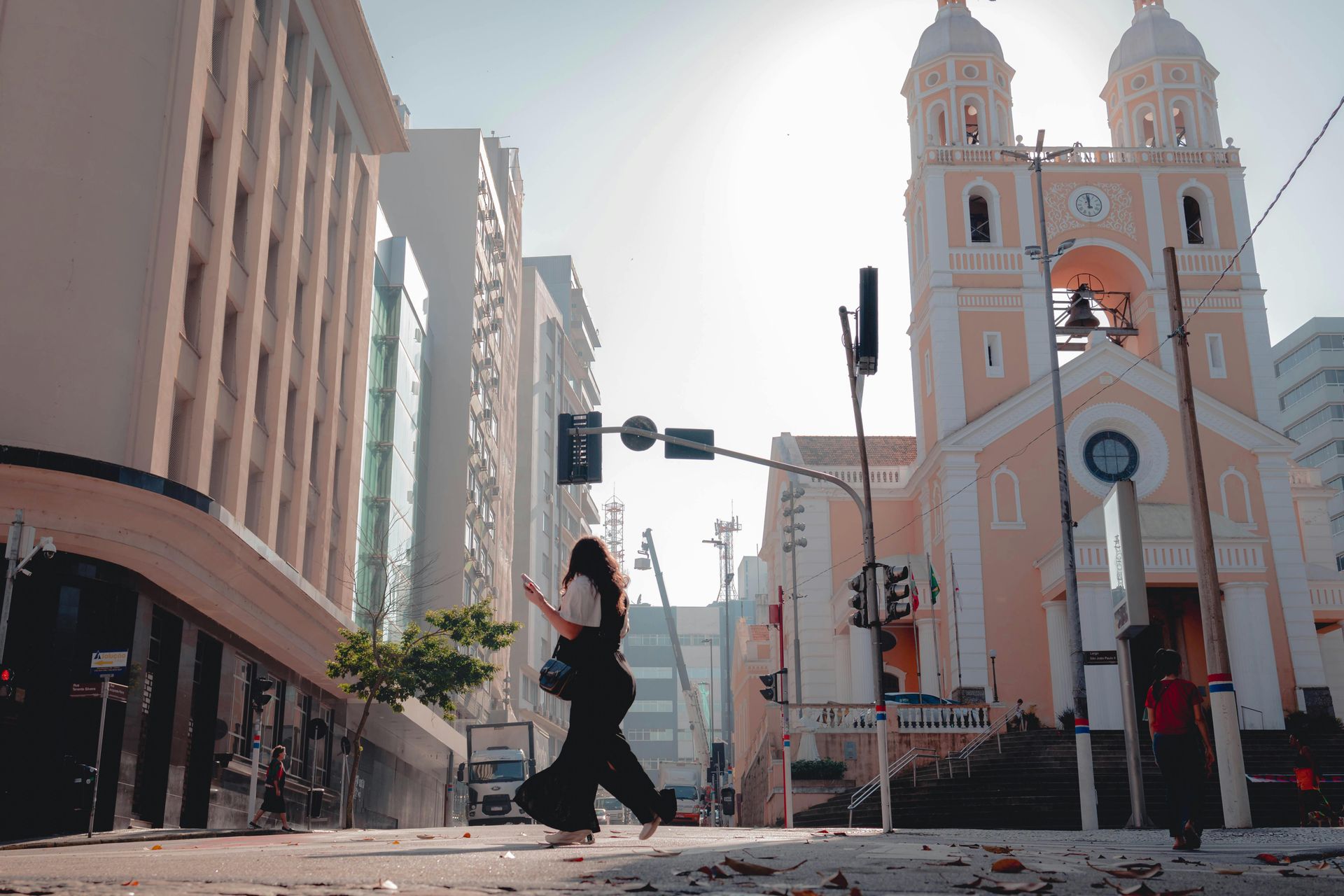 Catedral Metropolitana com pedestre atravessando a rua em dia ensolarado.