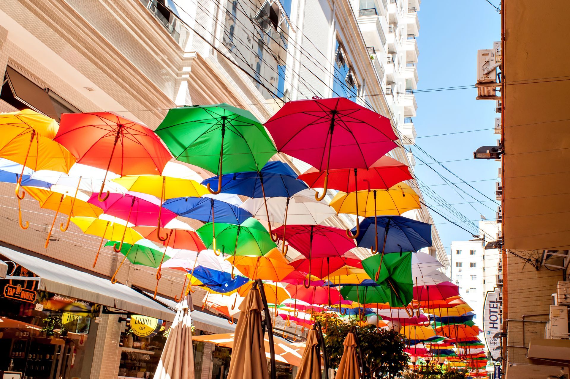 Rua com guarda-chuvas coloridos suspensos entre prédios