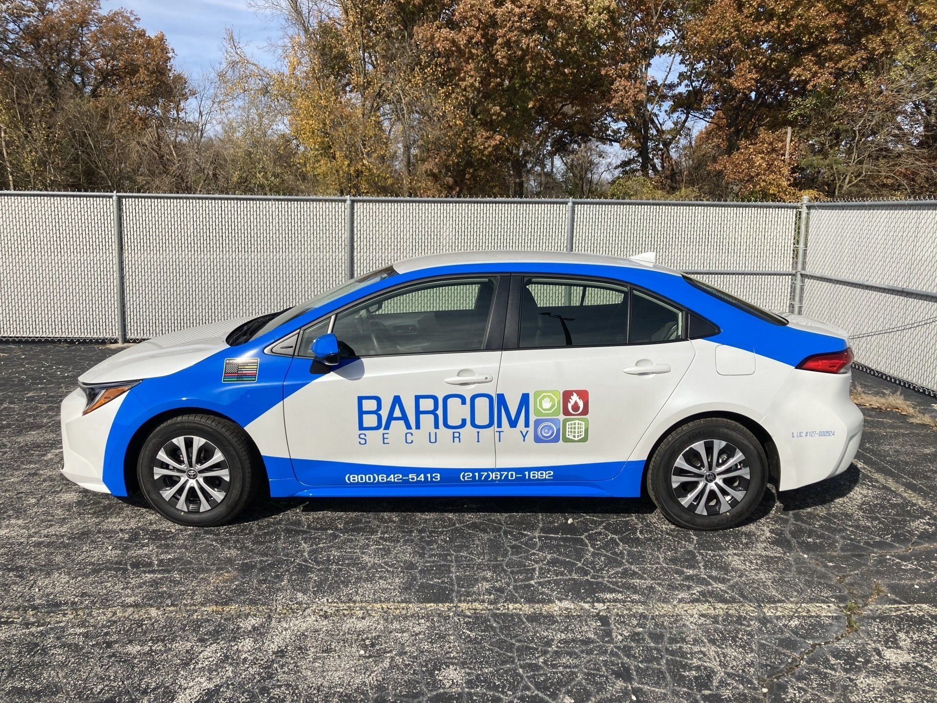 A white and blue car with the word barcom on the side is parked in a parking lot.