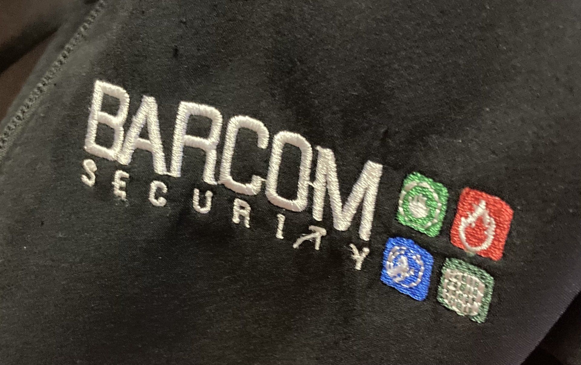 A black shirt with barcom security embroidered on it