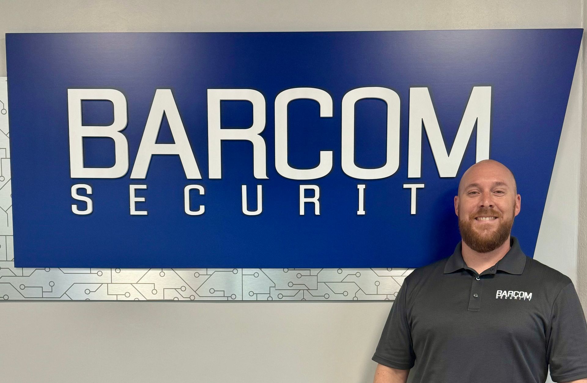 A man standing in front of a barcom security sign
