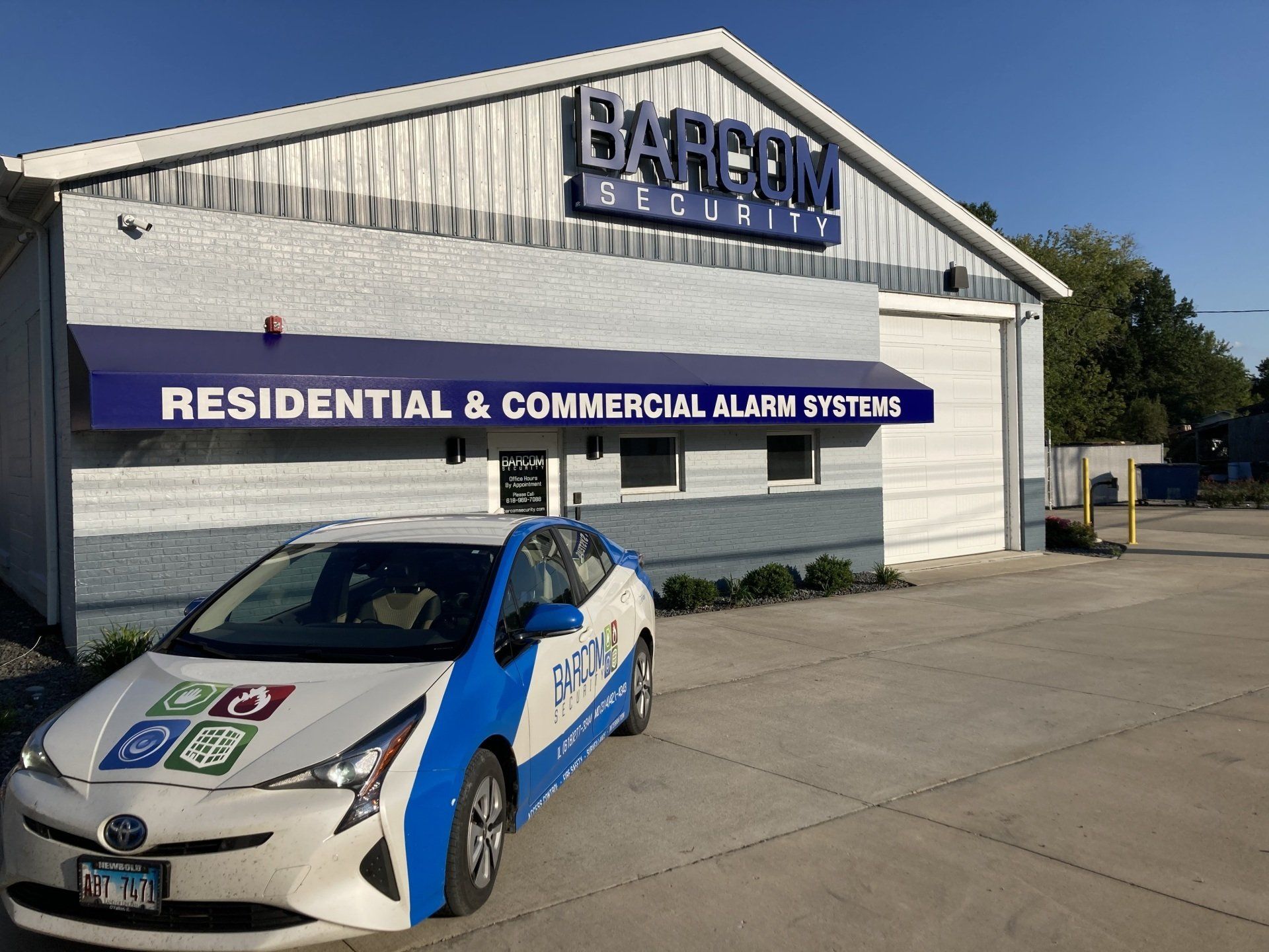 A car is parked in front of a building that says residential and commercial alarm systems
