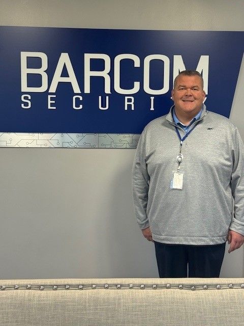 A man standing in front of a sign that says barcom security