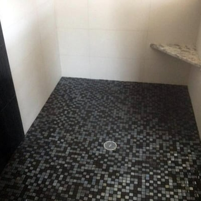 A bathroom with a black mosaic tile floor and a sink.