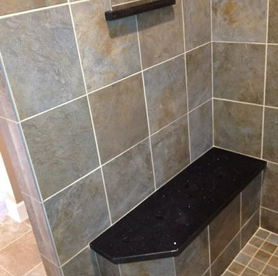 A black bench in a shower with tiled walls
