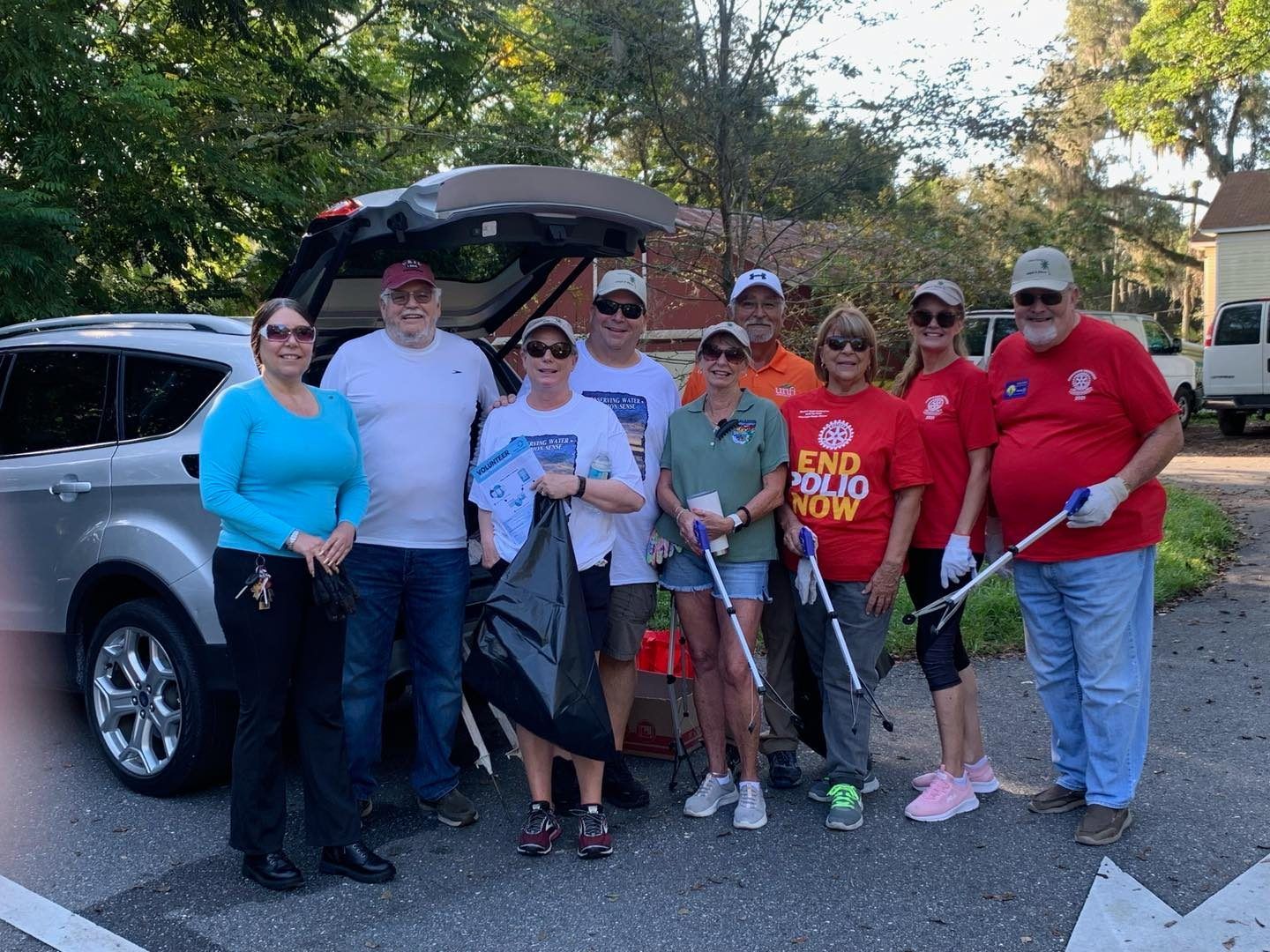 A group of people are posing for a picture in front of a car.