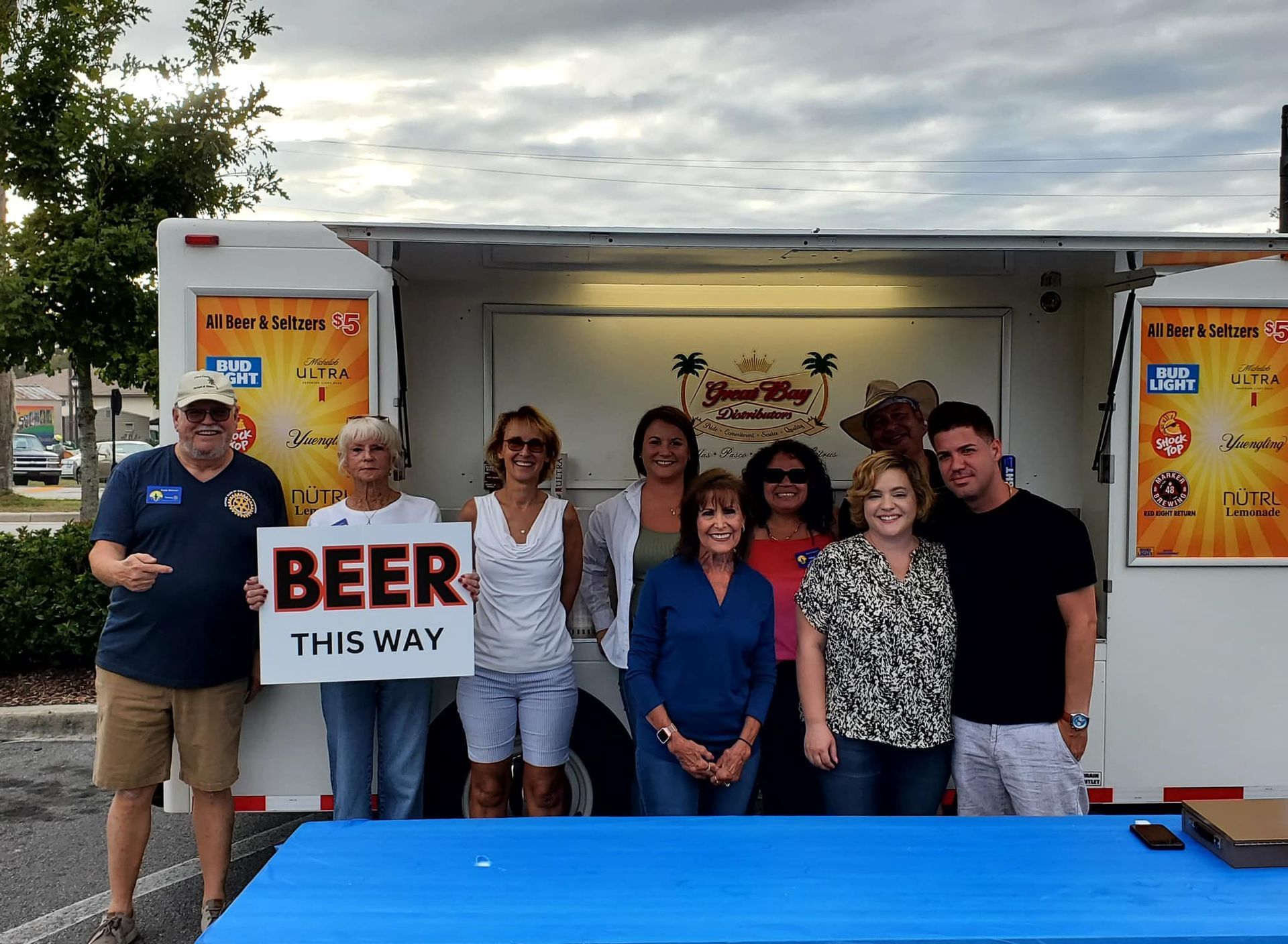 A group of people holding a sign that says beer this way