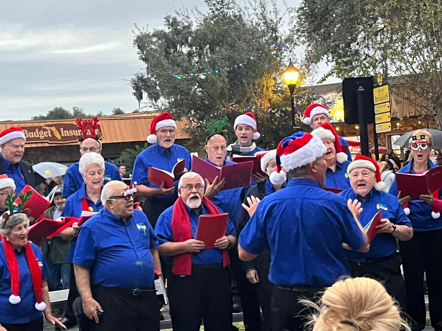 A group of people wearing santa hats are singing in a choir.