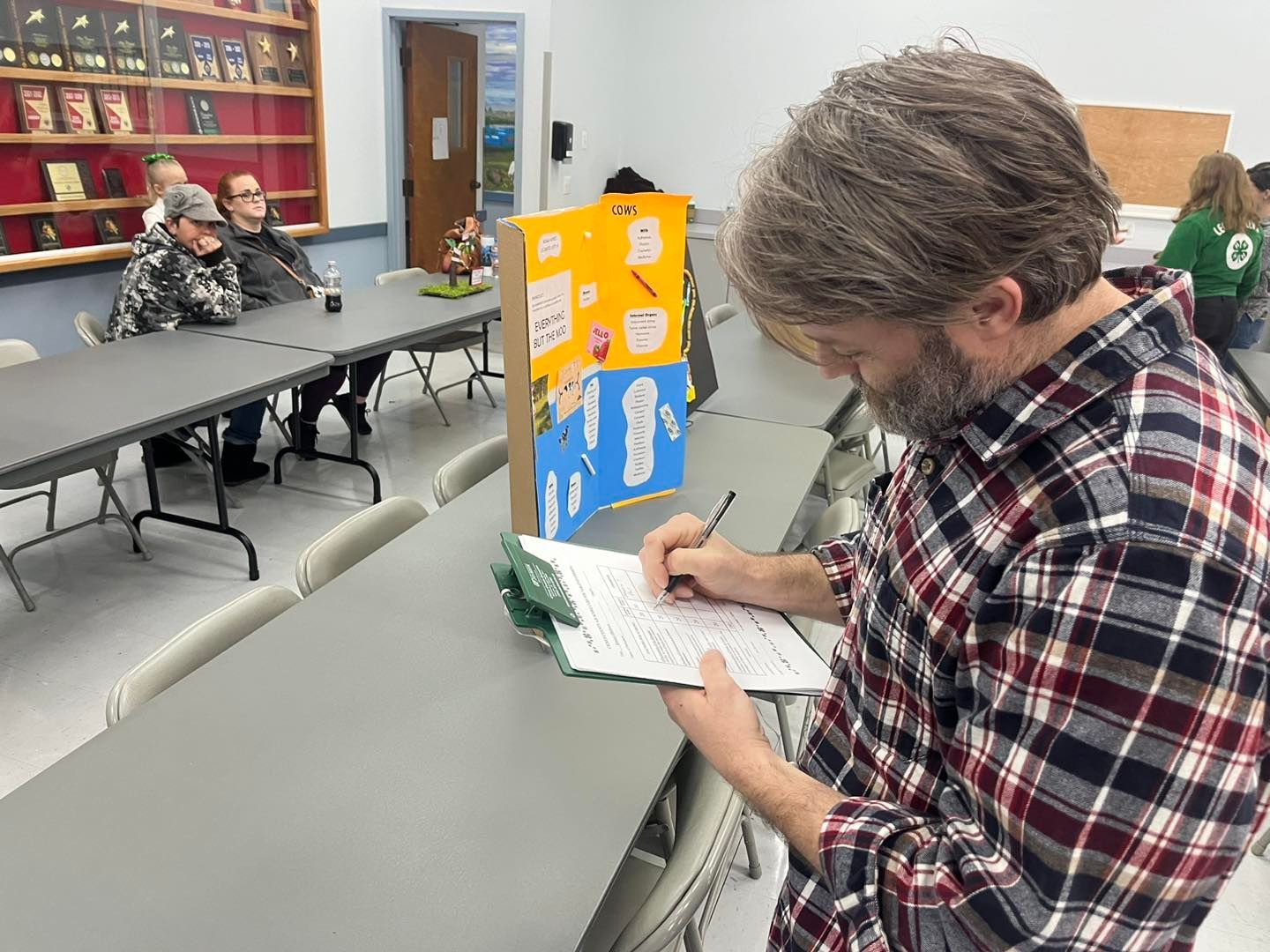 A man is sitting at a table writing on a piece of paper.