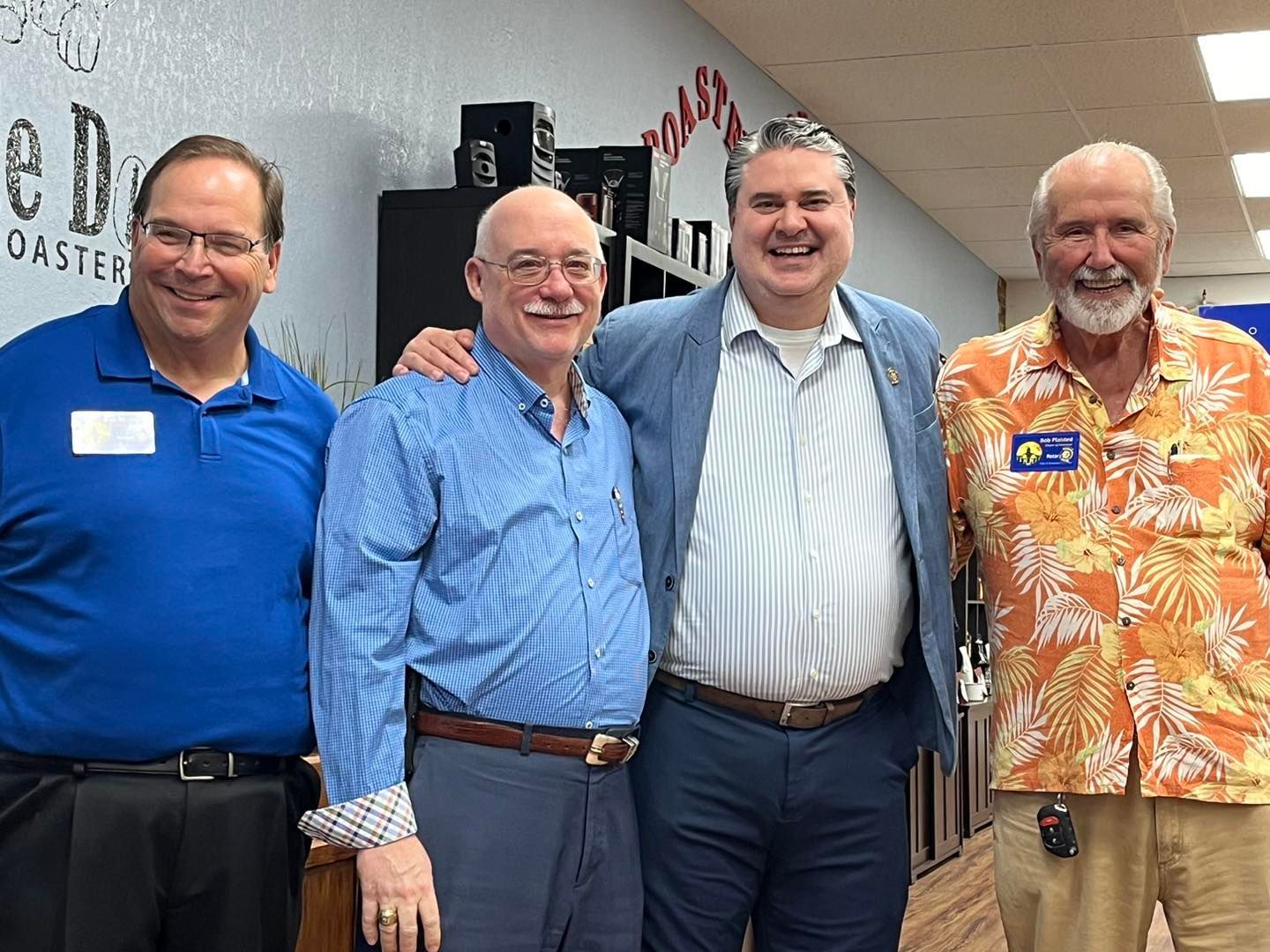 Four men are posing for a picture together in a room.