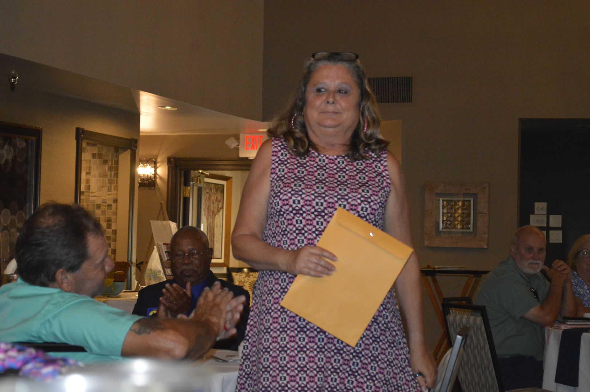 A woman is standing in a room holding an envelope.