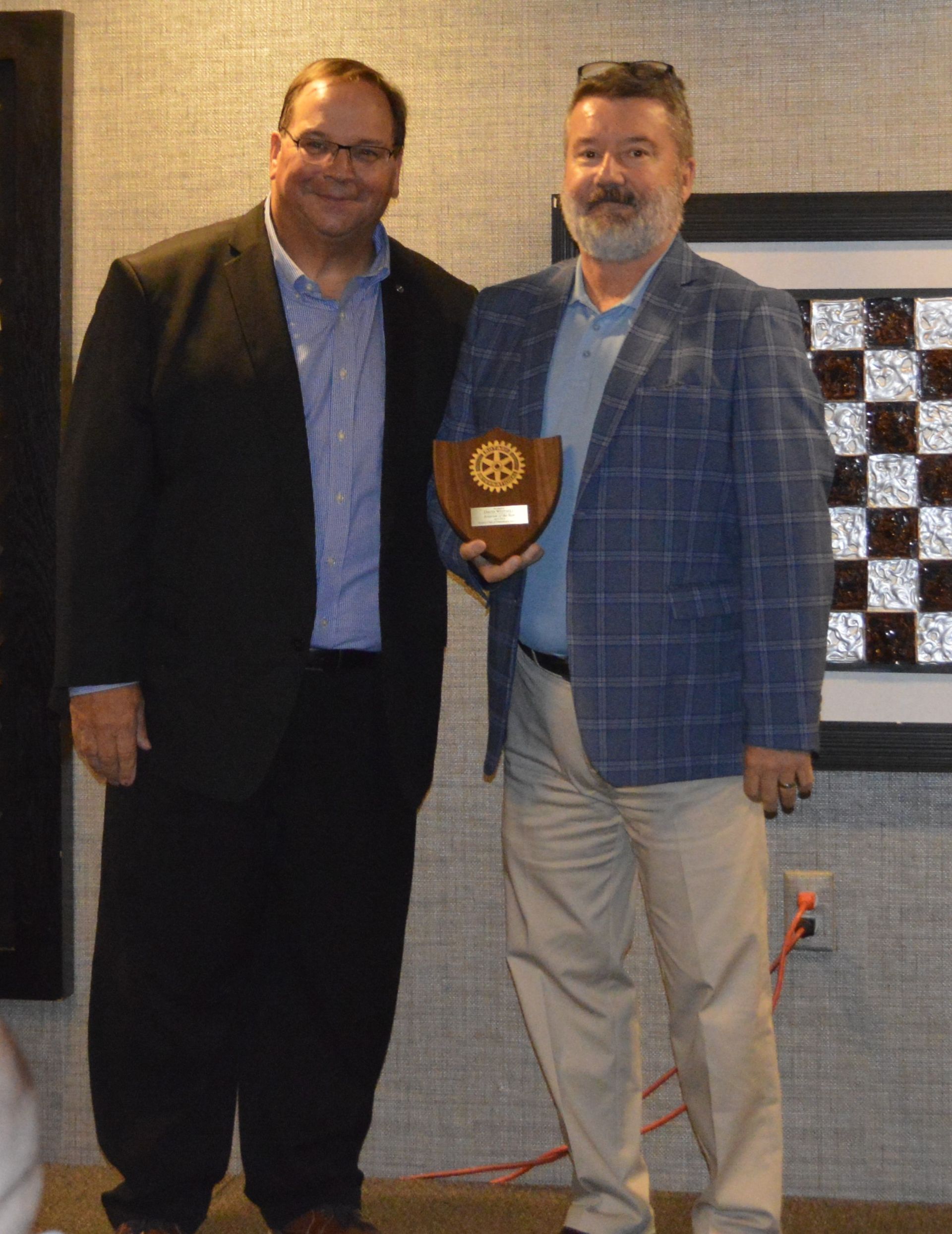 Two men are standing next to each other holding a plaque in front of a chess board.