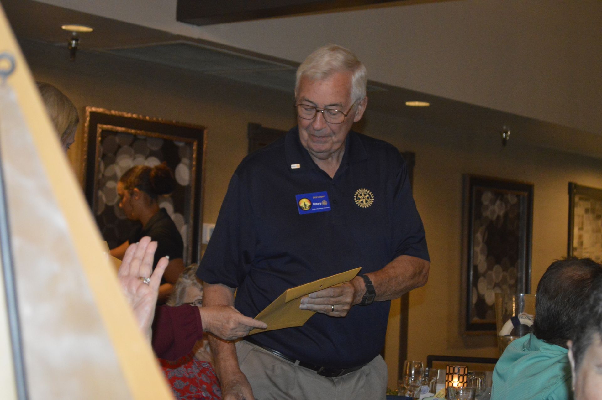 A man in a blue shirt is holding a piece of paper in a room.