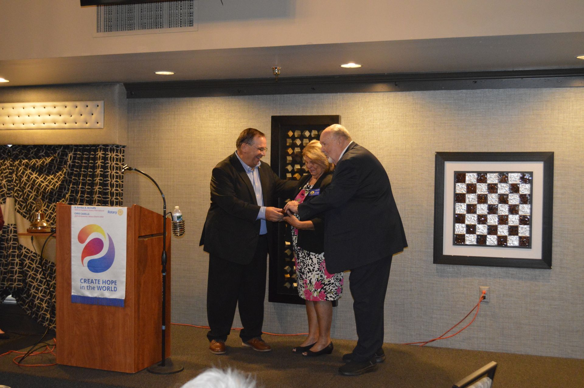 Two men and a woman are standing in front of a podium.