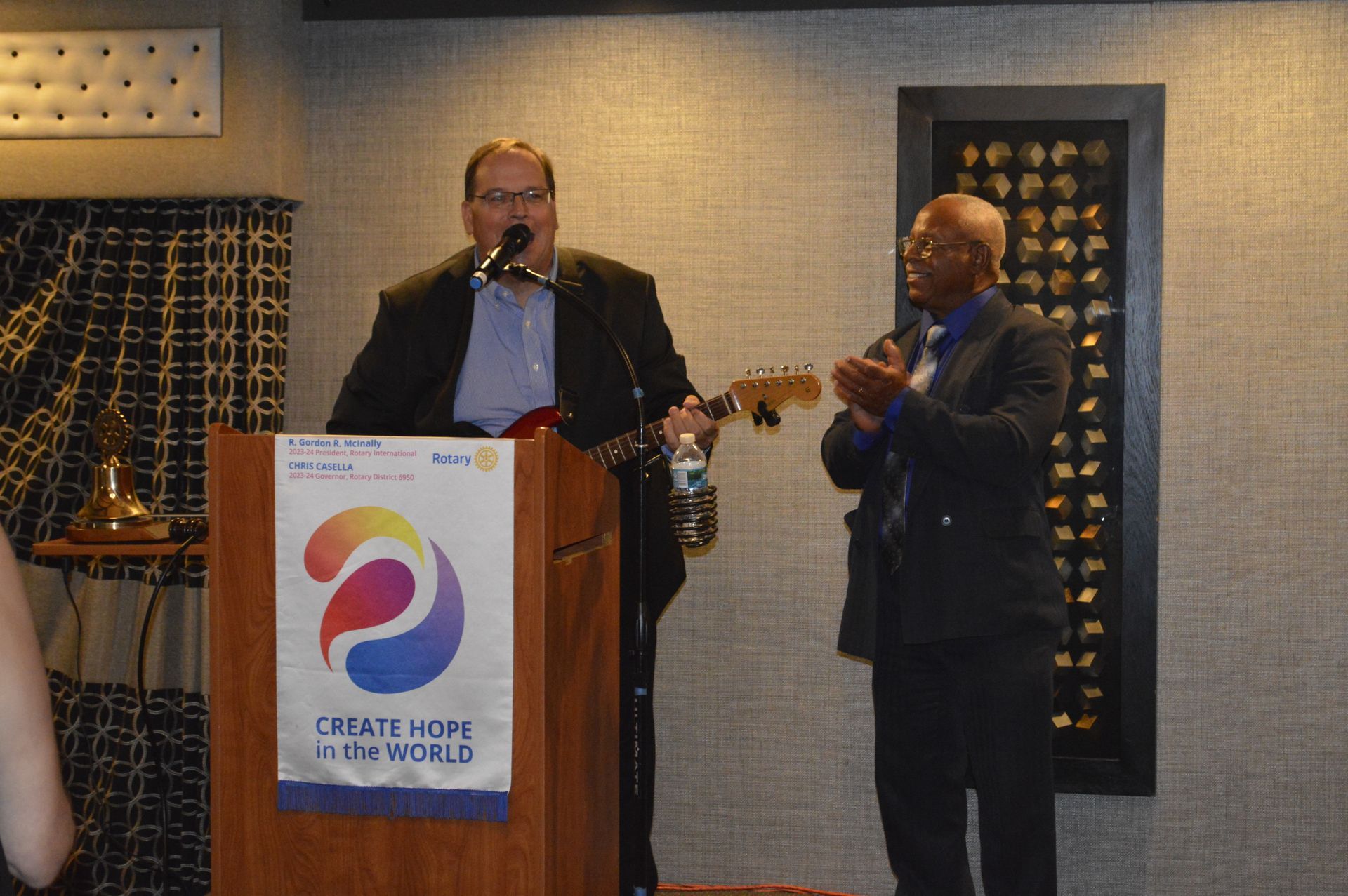 Two men are standing at a podium with a sign that says create hope in the world