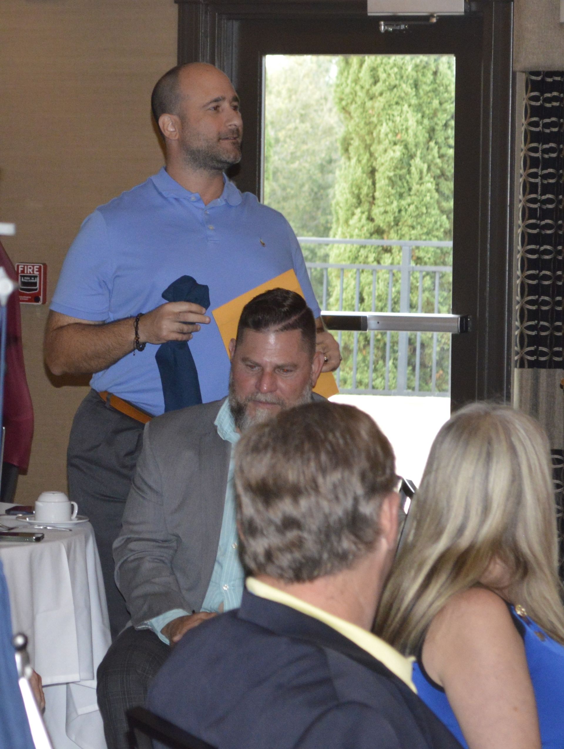 A man in a blue shirt is standing in front of a group of people