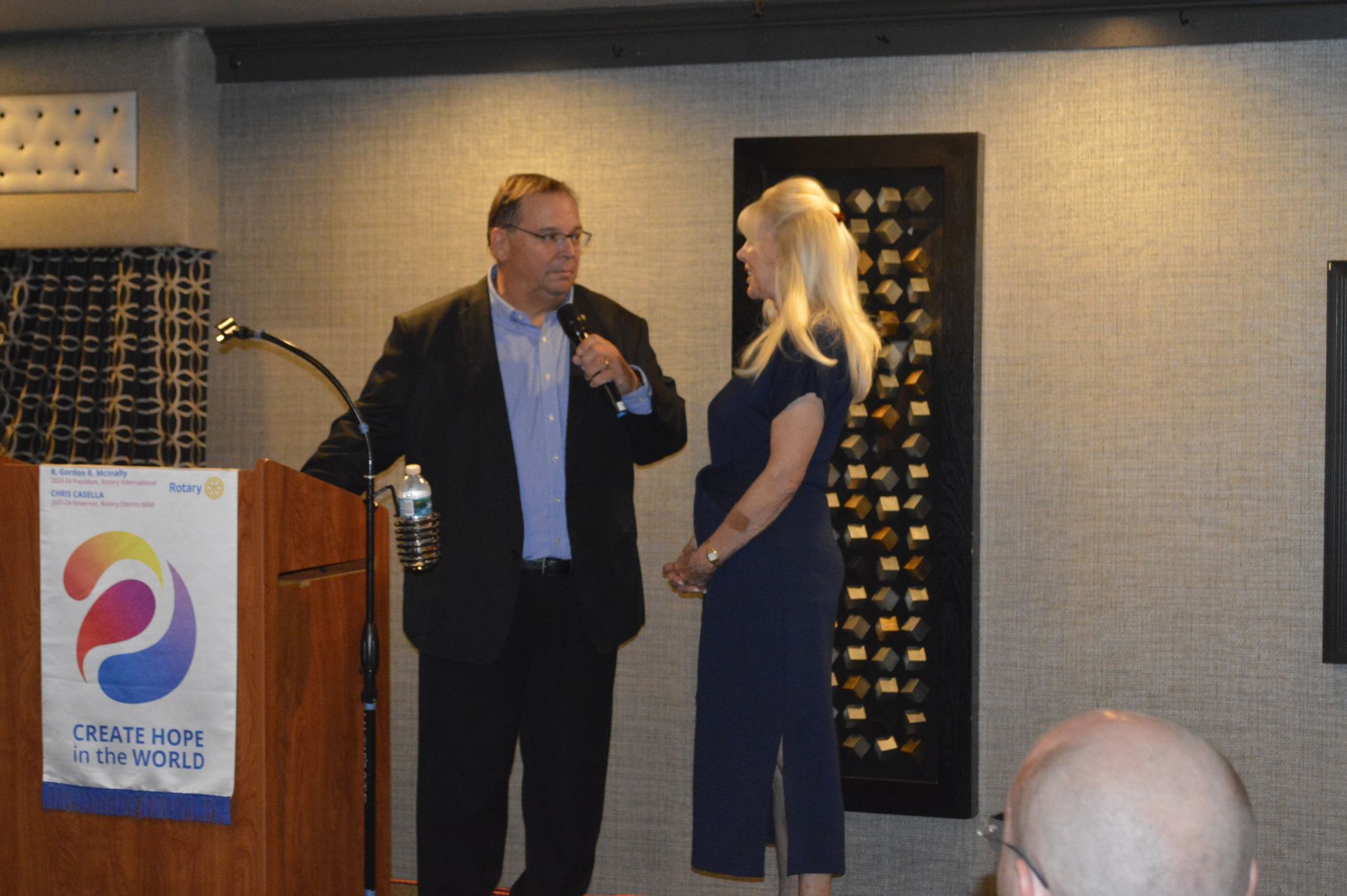 A man and a woman are standing in front of a podium talking to each other.