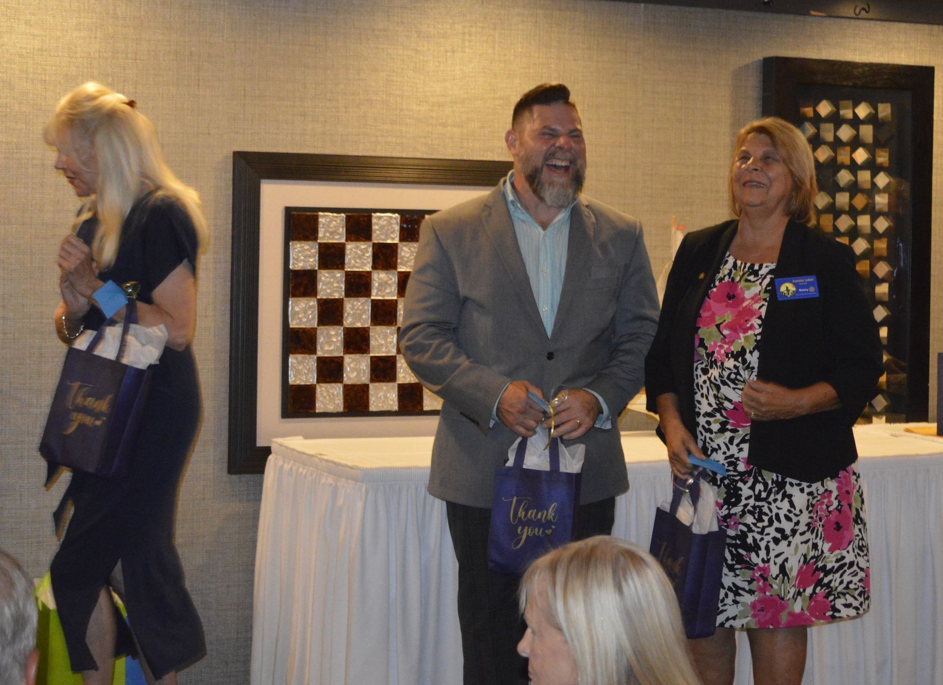 A man and two women are standing next to each other holding thank you bags.