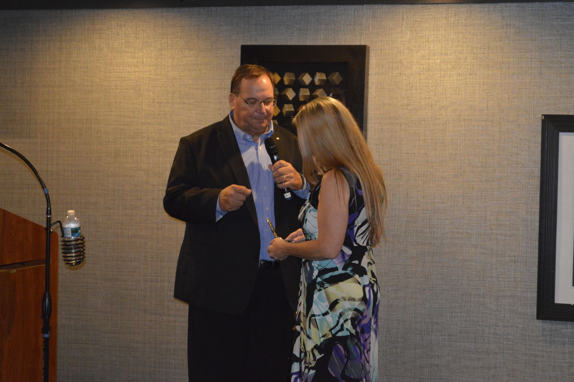 A man and a woman are standing next to each other in front of a microphone.