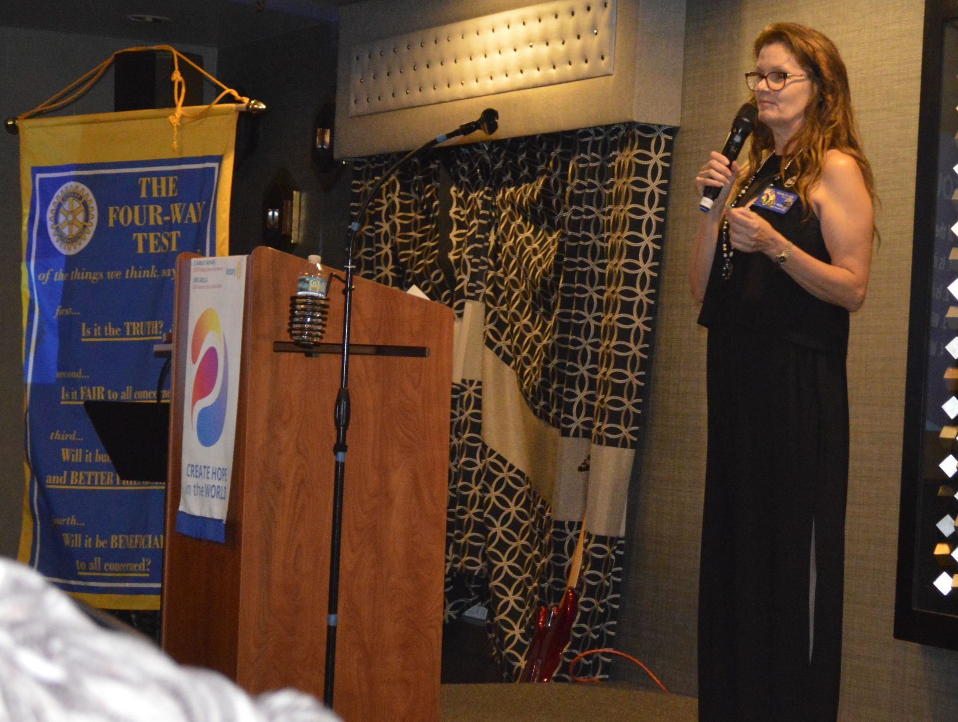 A woman stands at a podium in front of a banner that says the fourth test