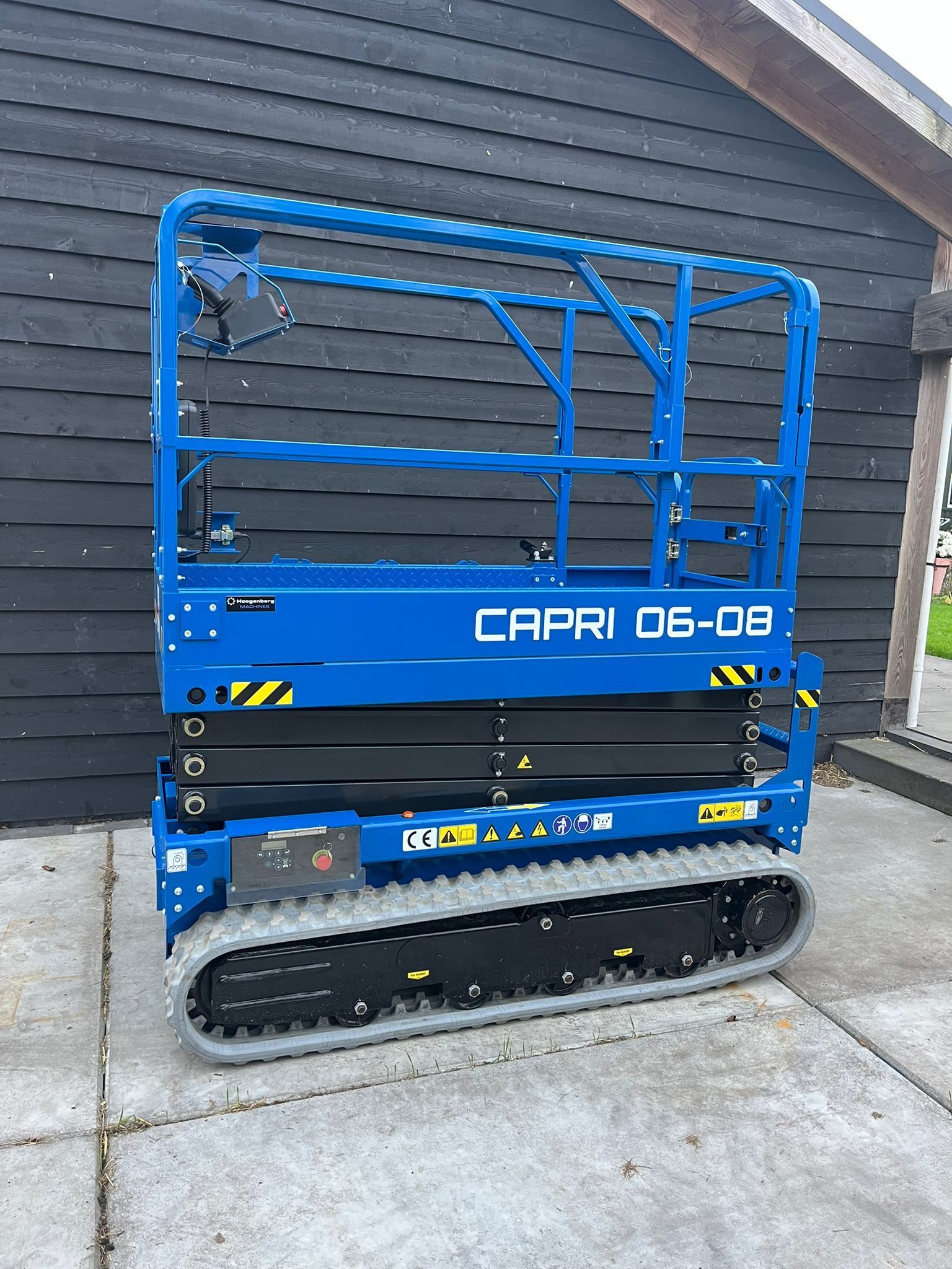 A red scissor lift is parked on the side of a road.
