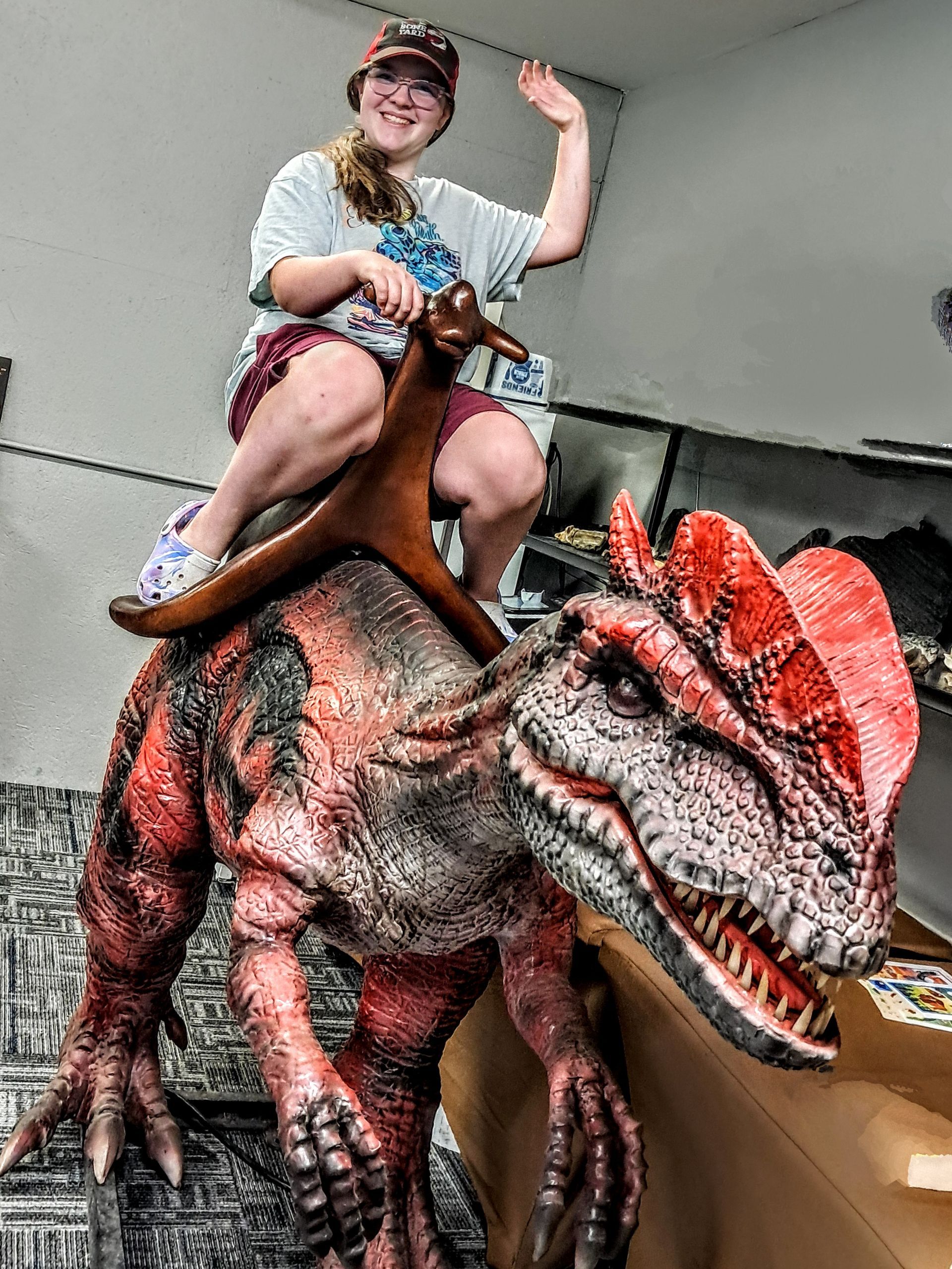 A woman is riding on the back of a dinosaur statue.
