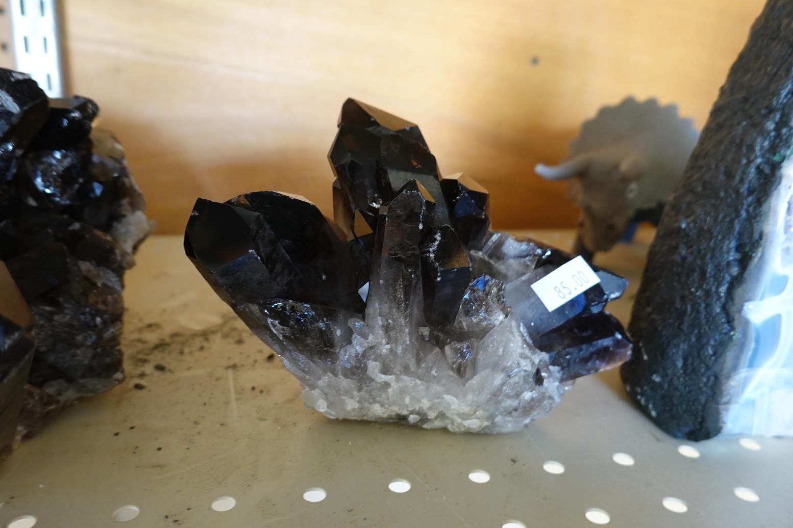 A black crystal is sitting on a table next to a toy dinosaur.