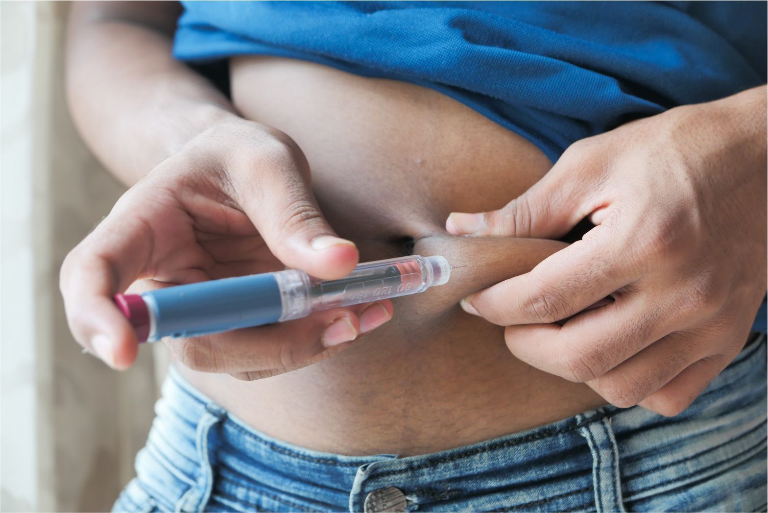 Hands using an insulin pen to inject medication into the abdomen