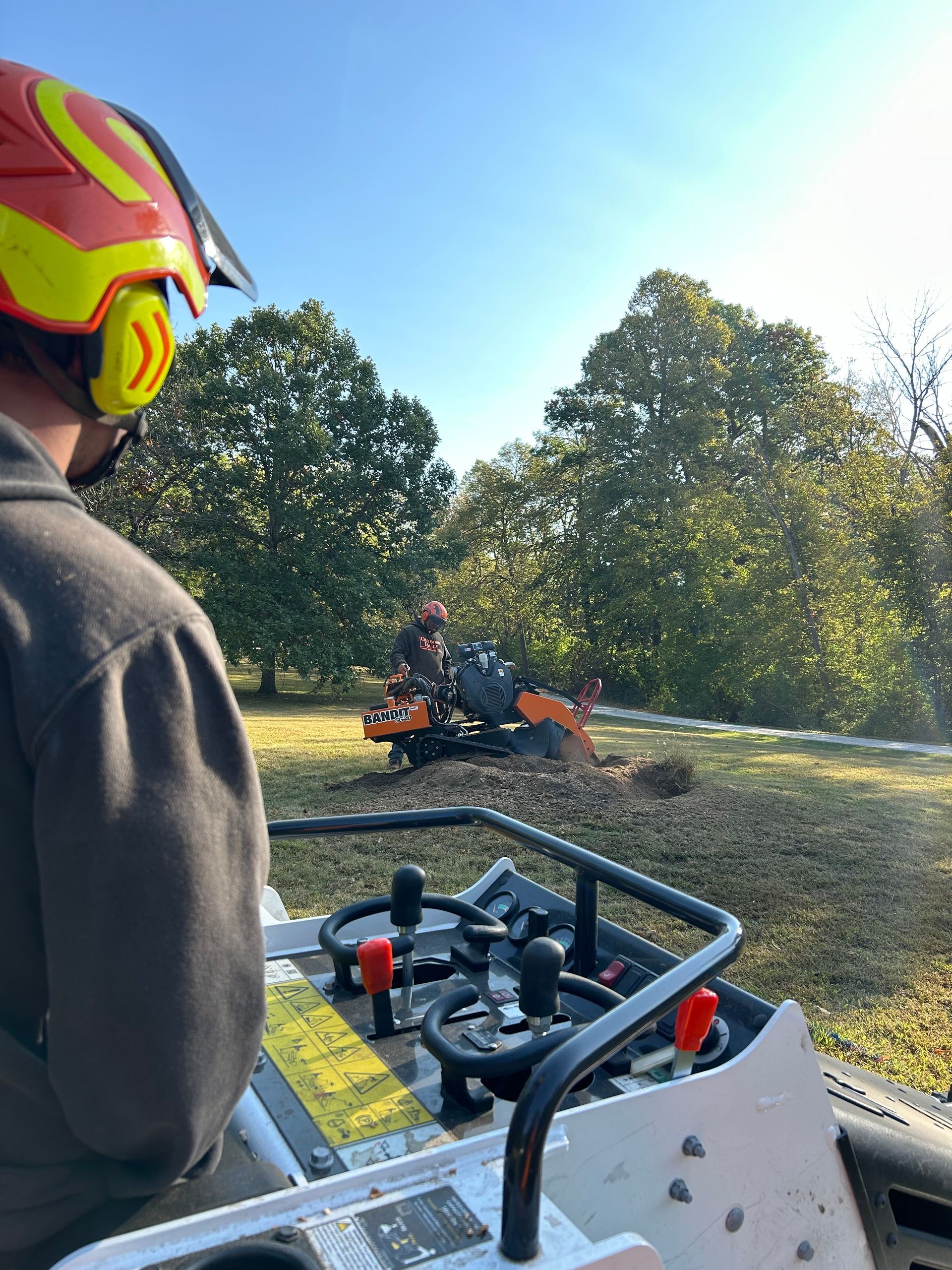 Person in neon helmet driving an ATV on a sunny dirt trail, with trees in the background.