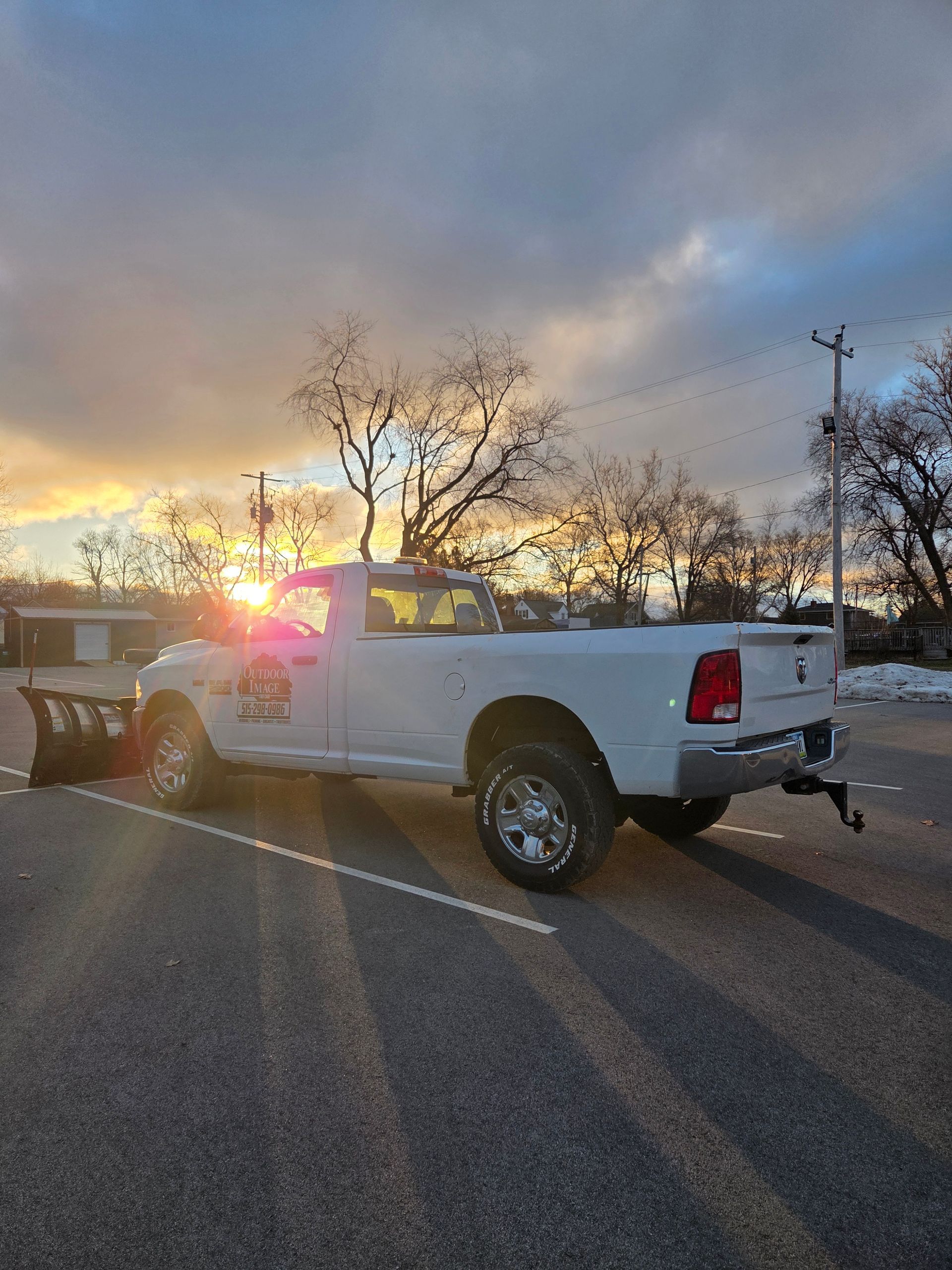 White pickup truck with tow rig and flashing emergency lights at sunset on a road