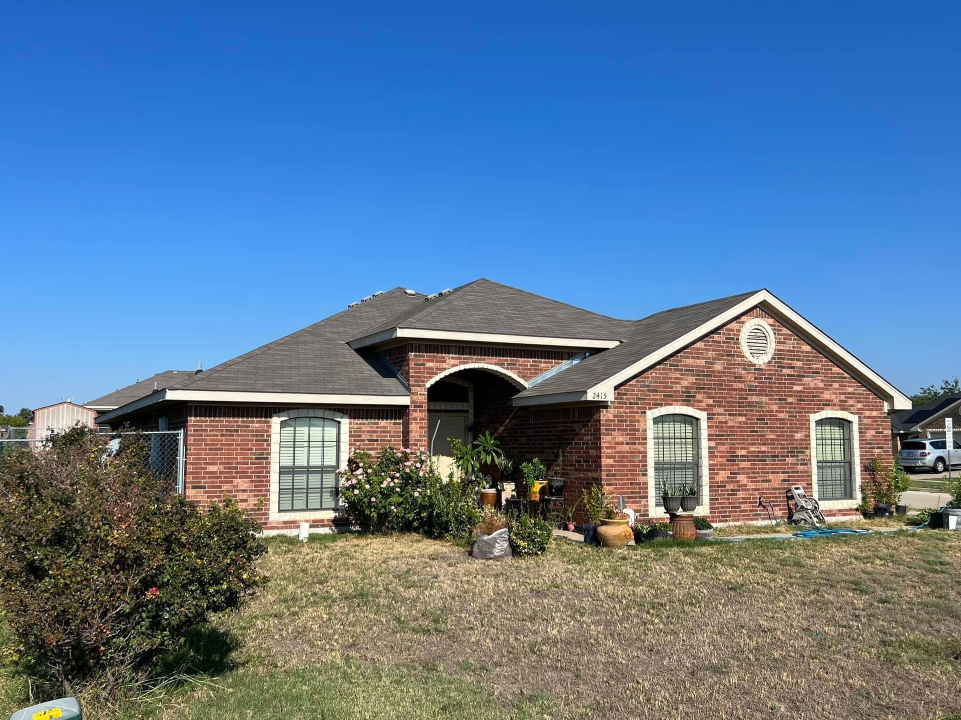 Brick house with a dark roof and a clear blue sky.
