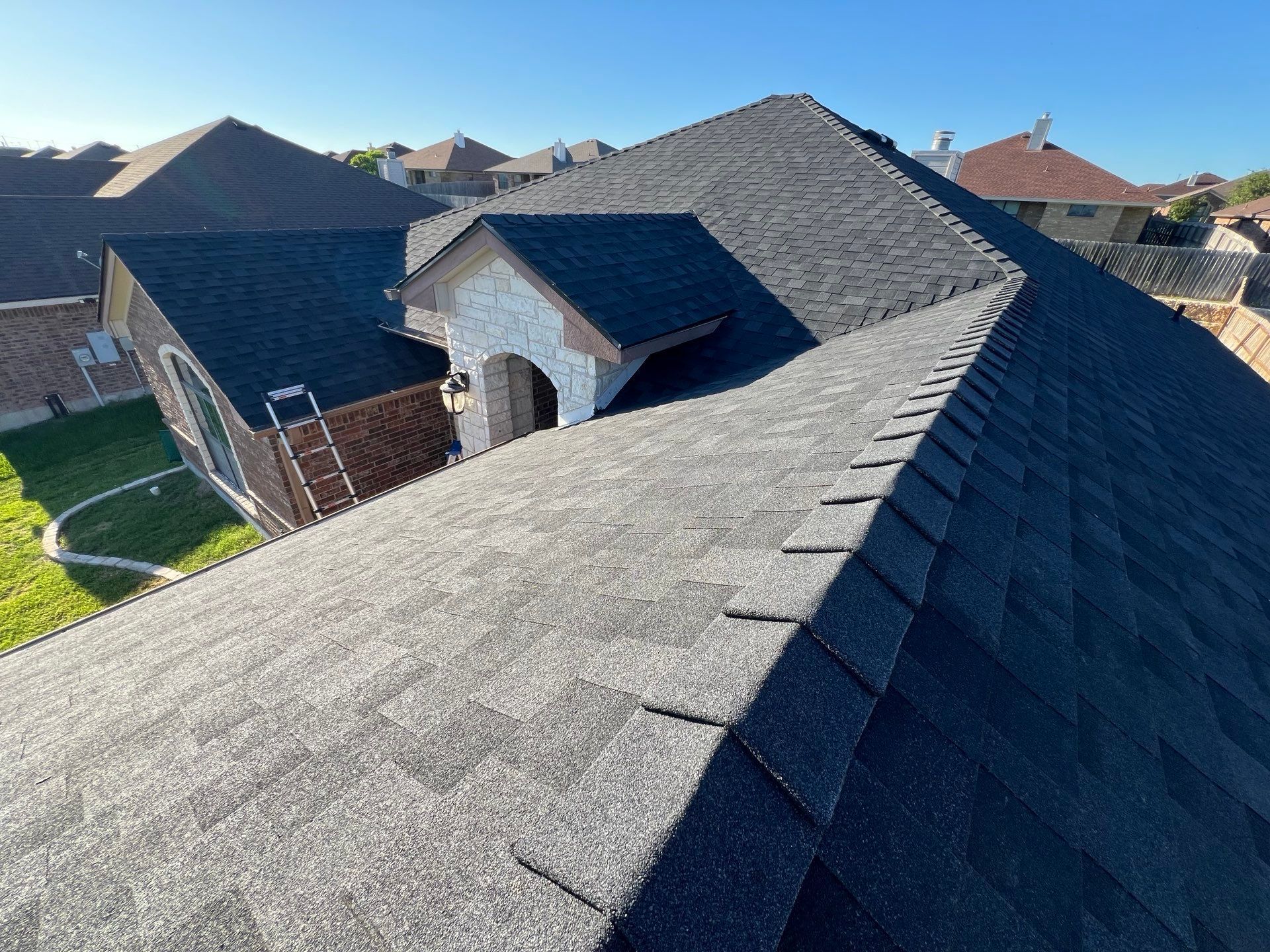Close-up of a residential asphalt shingle roof, angled view on a sunny day.
