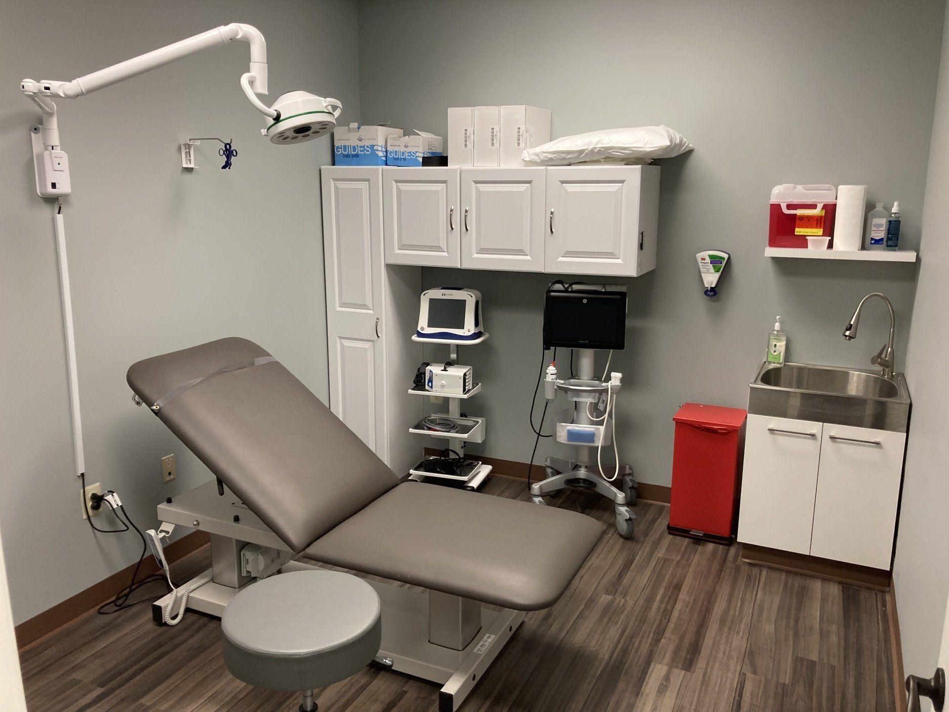 A doctor 's office with a couch and a sink.