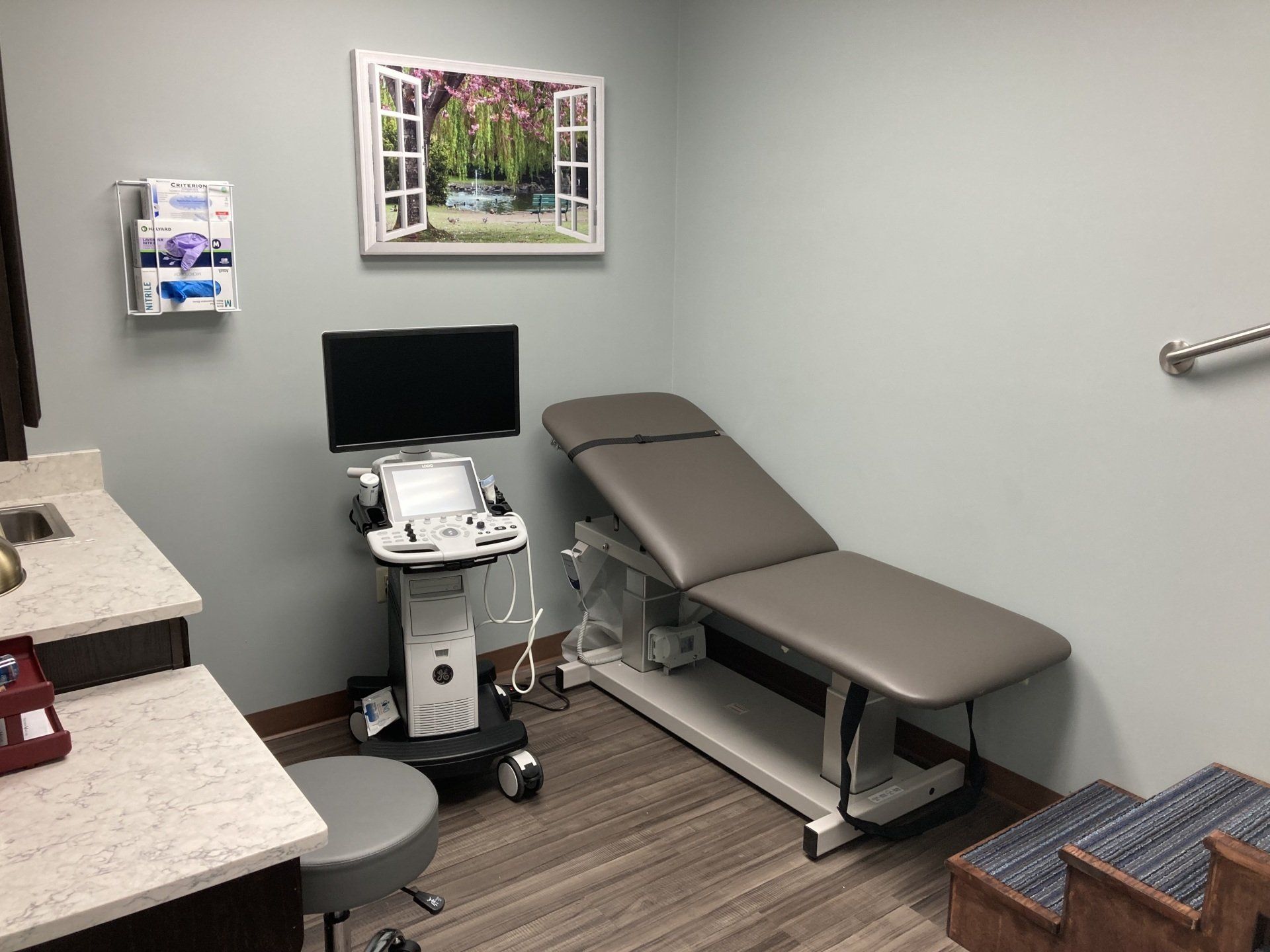A doctor 's office with an ultrasound machine and a bed.