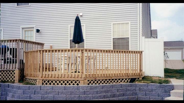 A house with a wooden deck and a blue umbrella