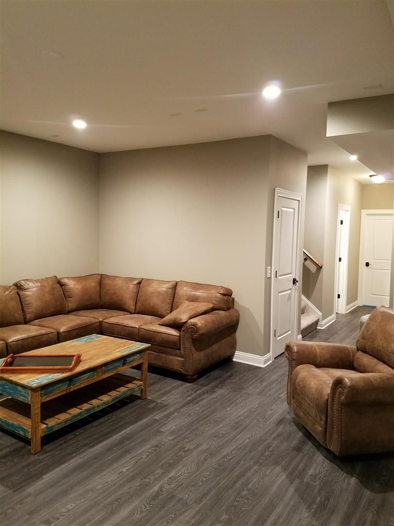 A living room with a couch , chair , coffee table and stairs.