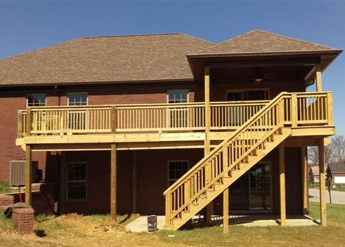 A brick house with a wooden deck and stairs leading up to it.