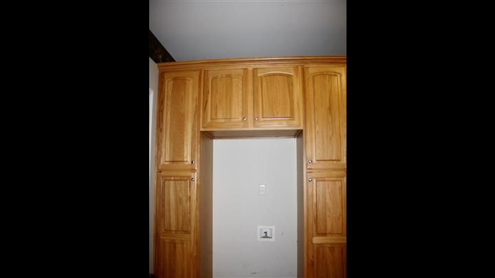 A kitchen with wooden cabinets and a white wall