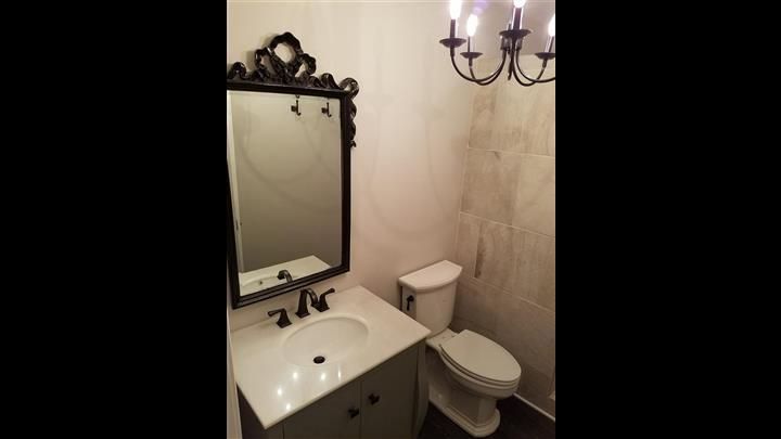 A bathroom with a sink , toilet , mirror and chandelier.
