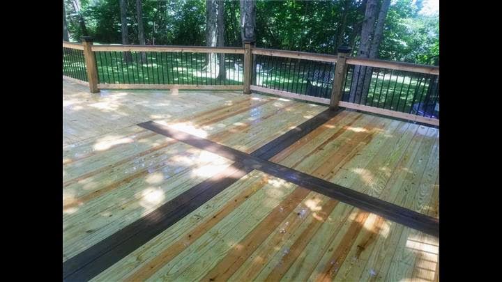 A wooden deck with a wooden railing and trees in the background.