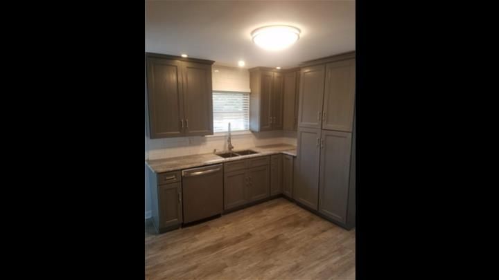 A kitchen with gray cabinets , a sink , and a dishwasher.