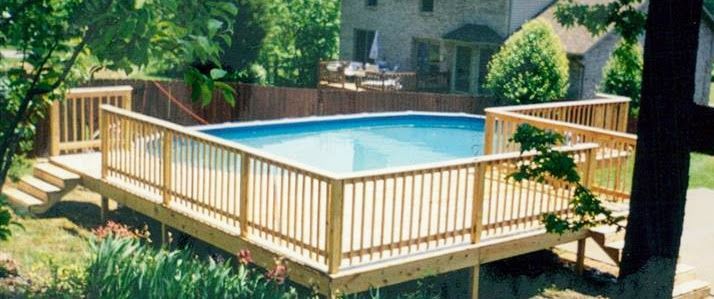 A large swimming pool with a wooden deck surrounding it