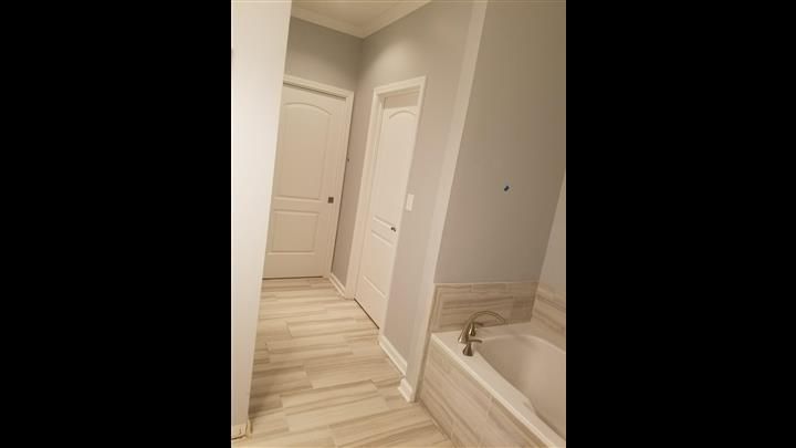 A bathroom with a tub and a hallway leading to it.