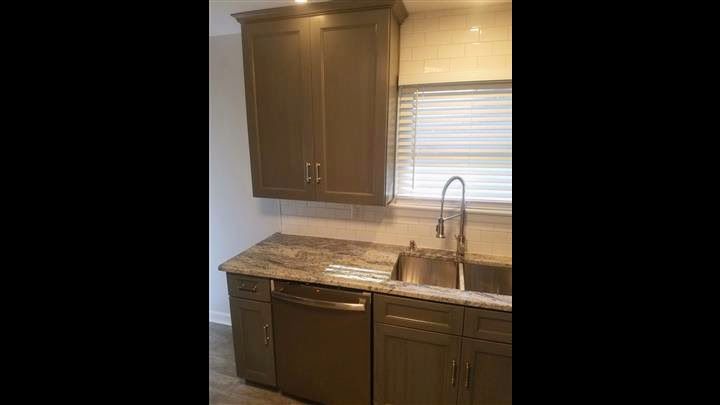 A kitchen with a sink , cabinets , and a window.